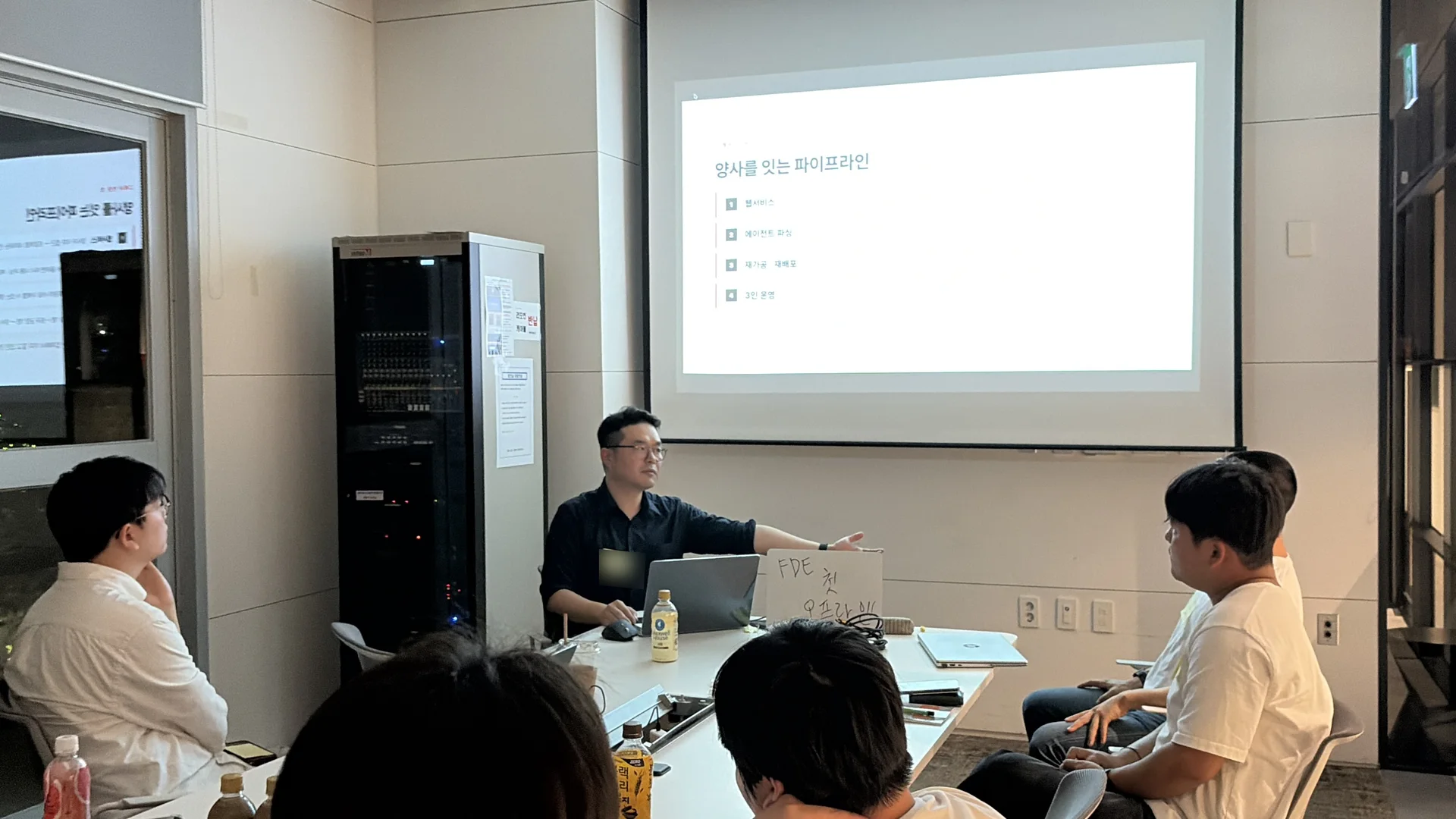 첫 케이스 토크에서 한 참가자가 양사를 잇는 파이프라인 사례를 설명하고 참가자들이 둘러앉아 듣는 모습